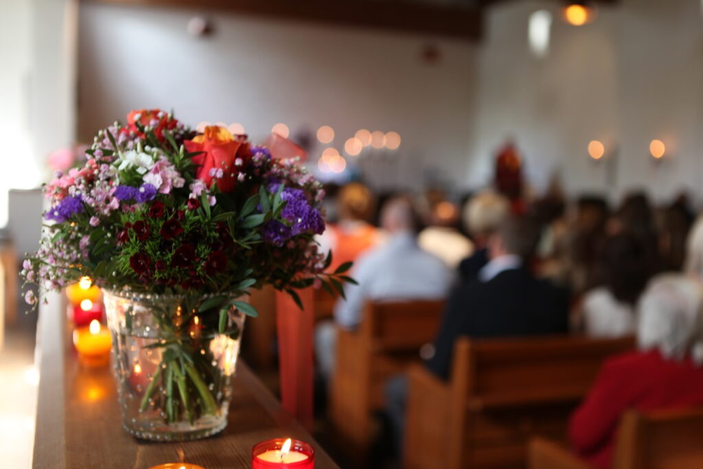 Floral arrangement and lit candles inside a church during a funeral service